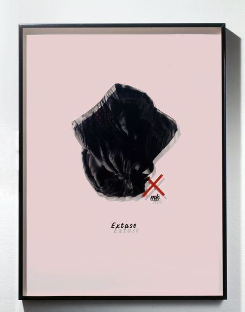 Mixed media. A photograph of a black, collared woman’s shirt or robe has been printed onto a piece of Plexiglass and mounted in a frame so it casts a shadow on the pastel pink mat behind it, creating double vision. The word “Extase” is below.